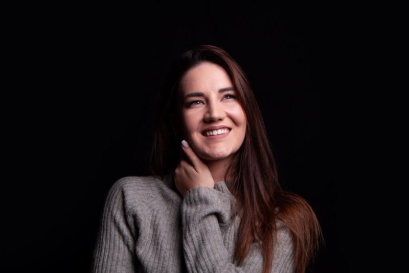 Studiofoto einer jungen Frau mit verträumtem Lächeln.