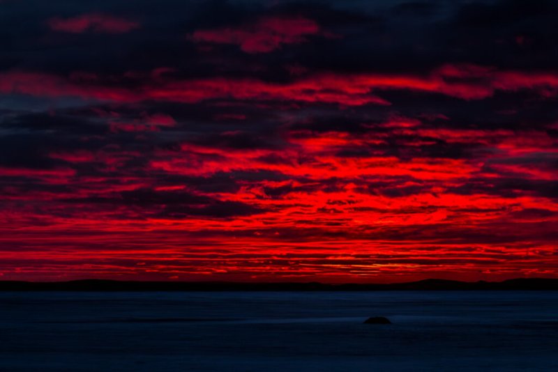 Foto eines dramatischen Sonnenuntergangs über einer Schneelandschaft mit tiefroten Wolken