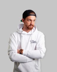 Branding-Foto: Junger Mann in urbaner Streetwear von "Platea", trägt eine weiße Kapuzenjacke und schwarze Snapback Cap.