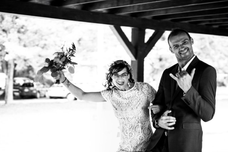 Alt-Text: Fröhliches Brautpaar wirft den Brautstrauß in einem stilvollen Schwarz-Weiß-Foto