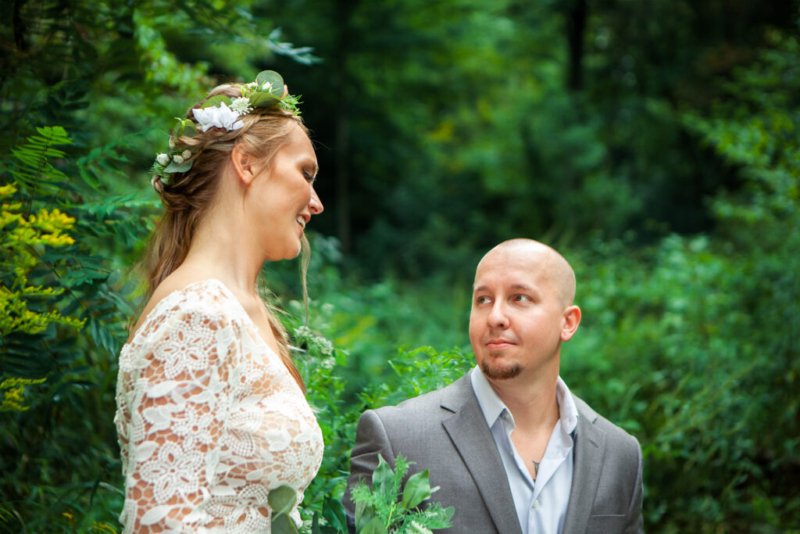 Glückliches Brautpaar im Wald, Bräutigam schaut liebevoll die lächelnde Braut an.