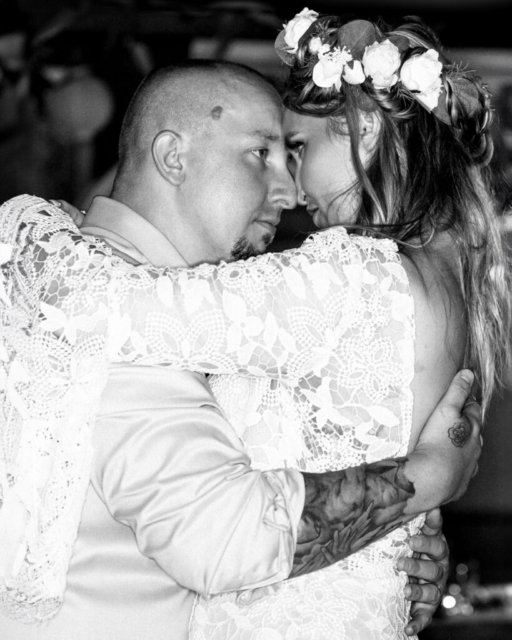 Ein emotionales Schwarz-Weiß-Foto eines Brautpaares, das während ihres Hochzeitstanzes eng umschlungen ist.