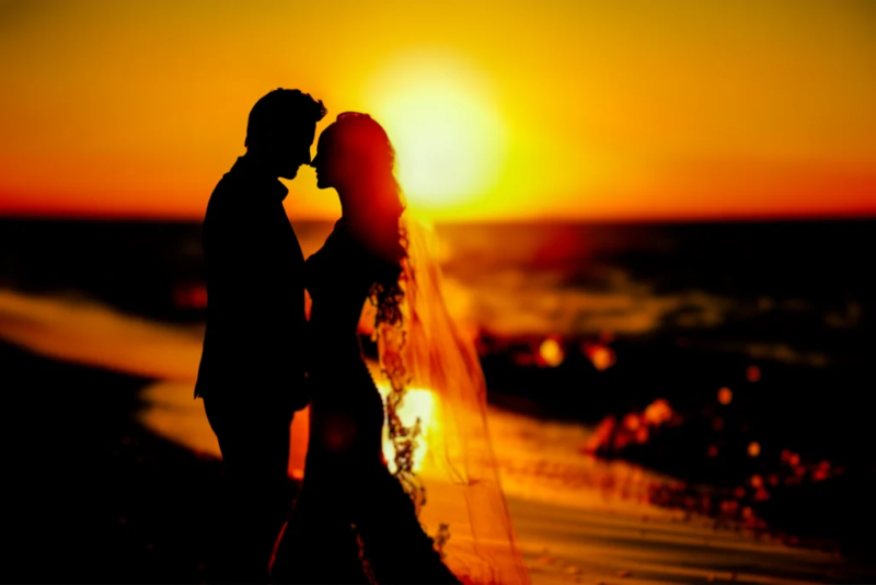 Silhouette eines Hochzeitspaares am Strand bei Sonnenuntergang.