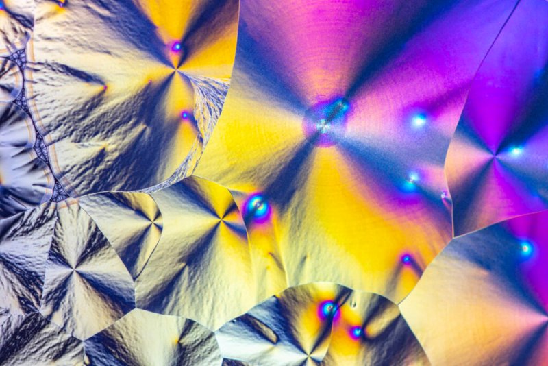Farbenfrohe Ascorbinsäure-Kristalle bilden abstrakte Mikrostrukturen.